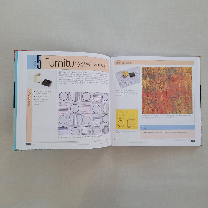 Open book with design page using furniture legs for stamping prints on a plain background