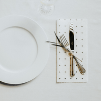White plate with silverware on a reusable bamboo towel as a napkin