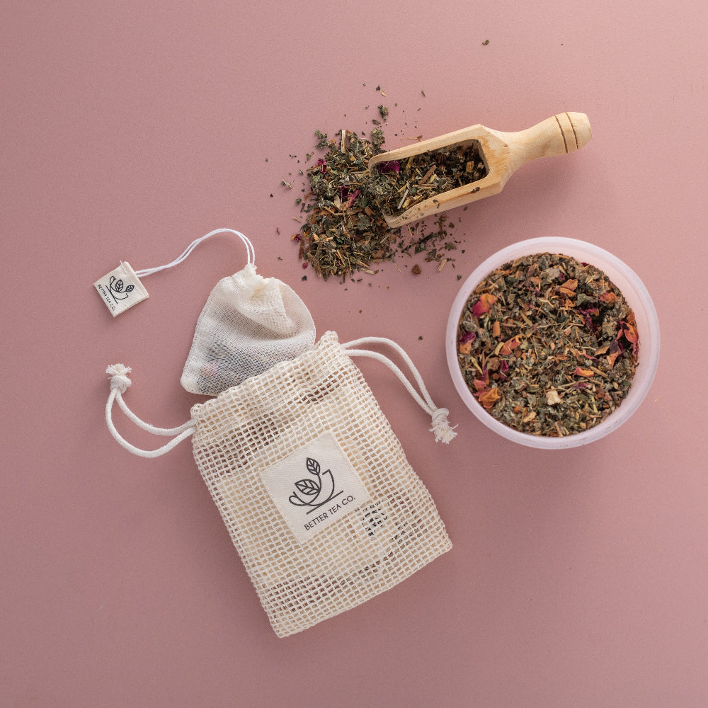 Teabags and loose tea and wooden scoop on a pink background