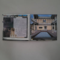 Spiral-bound book with architectural images and text on a gray background
