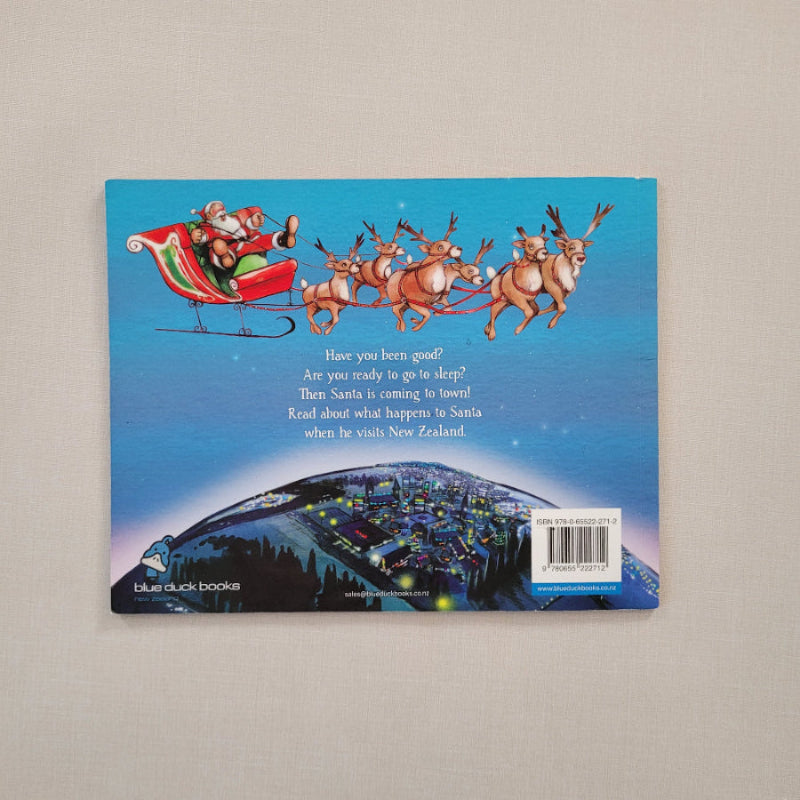 The back cover of a children's book  featuring an illustration of Santa Claus in a sleigh with reindeer against a blue sky, 