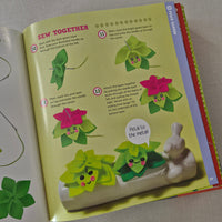 Children's craft book with green floral patterns and sewing instructions on a grey surface