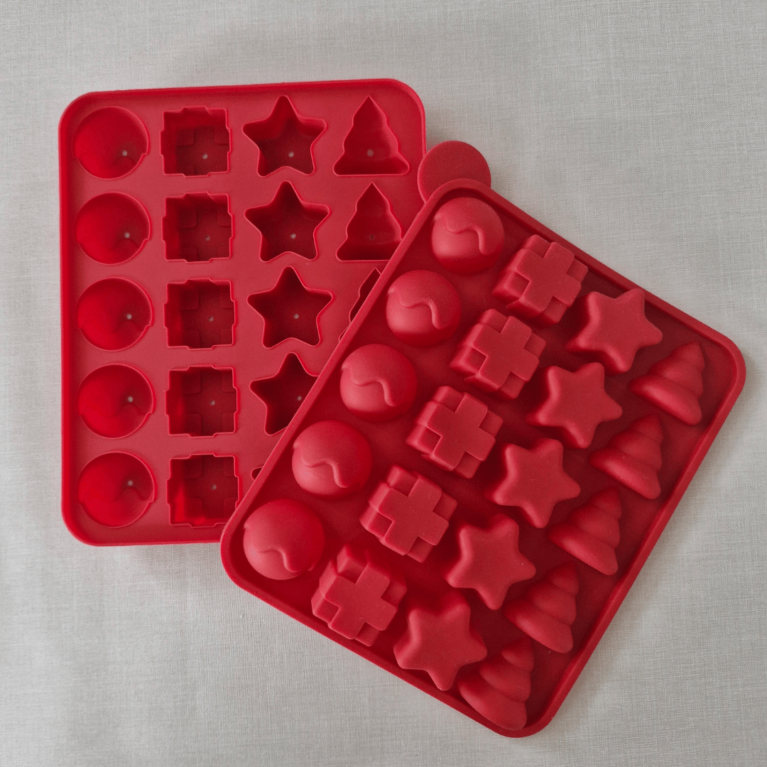 Red silicone mold trays with various shapes on a light gray background
