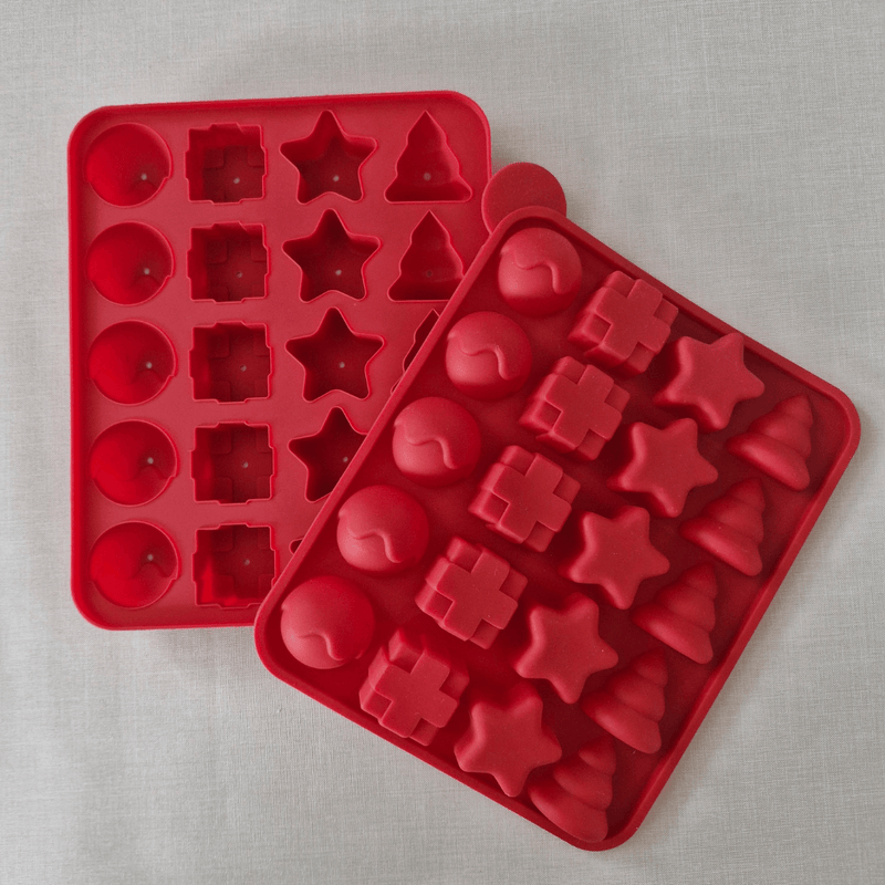 Red silicone mold trays with various shapes on a light gray background