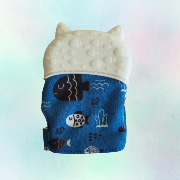 Reverse side of a silicone teething mitt designed to resemble a cat, with a blue patterned sleeve and a white silicone top.