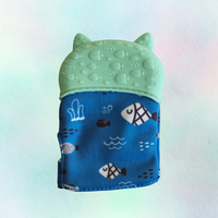 A silicone teething mitt designed to resemble a cat, with a blue patterned sleeve and a white silicone top.