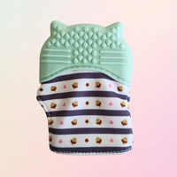 Green raccoon teething mitt with acorn pattern on a green background