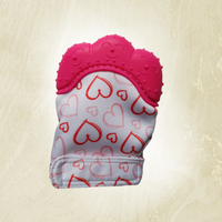A pink teething mitt with a heart pattern, designed to fit on a baby's hand.