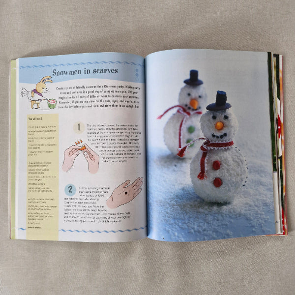 Open book showing a craft tutorial with snowmen and text on a beige surface