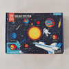 Solar system-themed puzzle box with colourful illustrations of planets and space elements on a grey background.