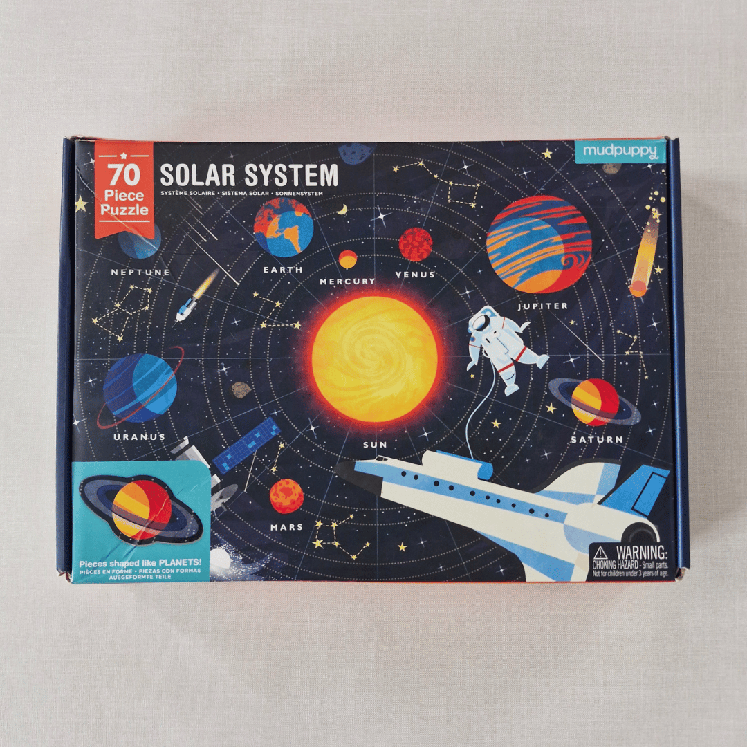 Solar system-themed puzzle box with colourful illustrations of planets and space elements on a grey background.