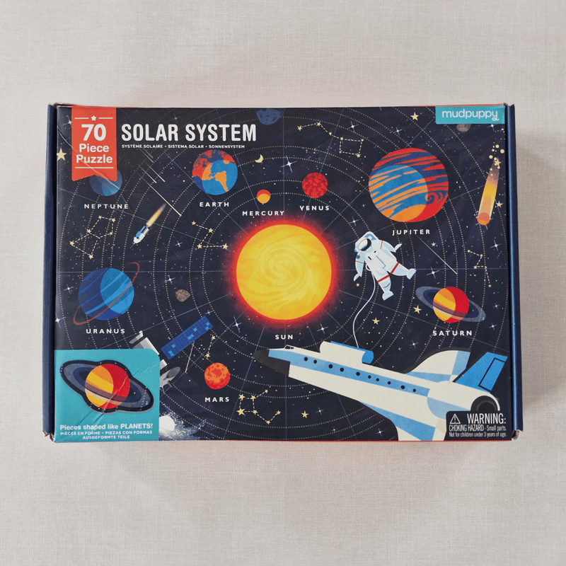 Solar system-themed puzzle box with colourful illustrations of planets and space elements on a grey background.