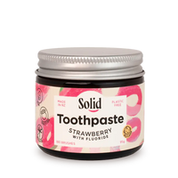 Jar of strawberry-flavored solid toothpaste with a visible brand label on a white background