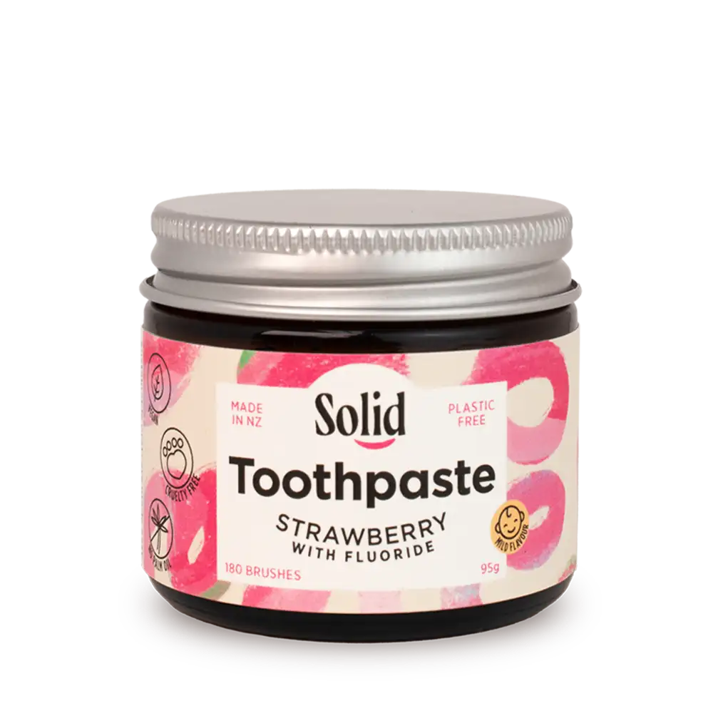 Jar of strawberry-flavored solid toothpaste with a visible brand label on a white background