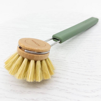 Dishwashing brush with wooden head and green handle on a white background