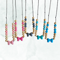 Colourful beaded teething necklaces with bow accents on a white background