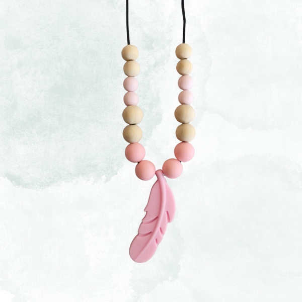 Necklace with wooden and pink beads and a silicone feather on a white background