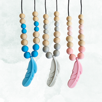 Three baby teething necklaces with colorful beads and feather ends on a white background