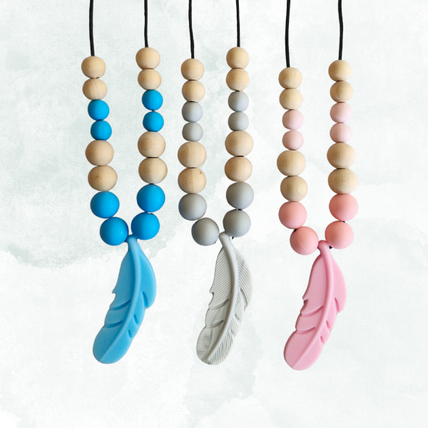 Three baby teething necklaces with colorful beads and feather ends on a white background