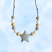 Teething necklace with star-shaped pendant and assorted beads against a light blue background