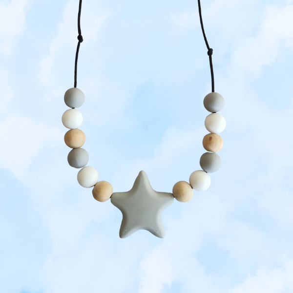 Teething necklace with star-shaped pendant and assorted beads against a light blue background