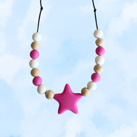 Teething necklace with pink star-shaped pendant and colorful beads against a light blue background