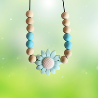 Teething necklace with wooden and silicone beads and a flower-shaped pendant on a gradient background