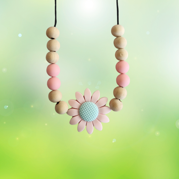 Teething necklace with wooden beads and a pink flower pendant on a gradient background