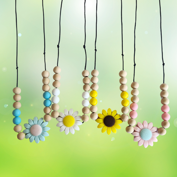 Colorful teething necklaces with wooden beads and flower-shaped charms on a gradient green background