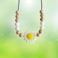 Teething necklace with wooden beads and a daisy flower pendant on a light green background
