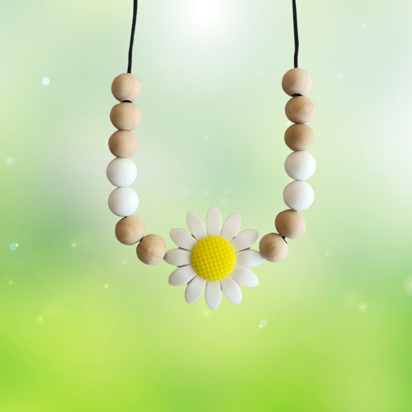 Teething necklace with wooden beads and a daisy flower pendant on a light green background