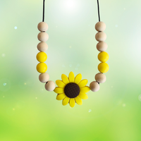 Teething necklace with wooden beads and a sunflower charm on a green background