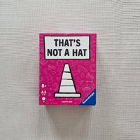 Board game box titled 'That's Not a Hat' on a gray fabric background