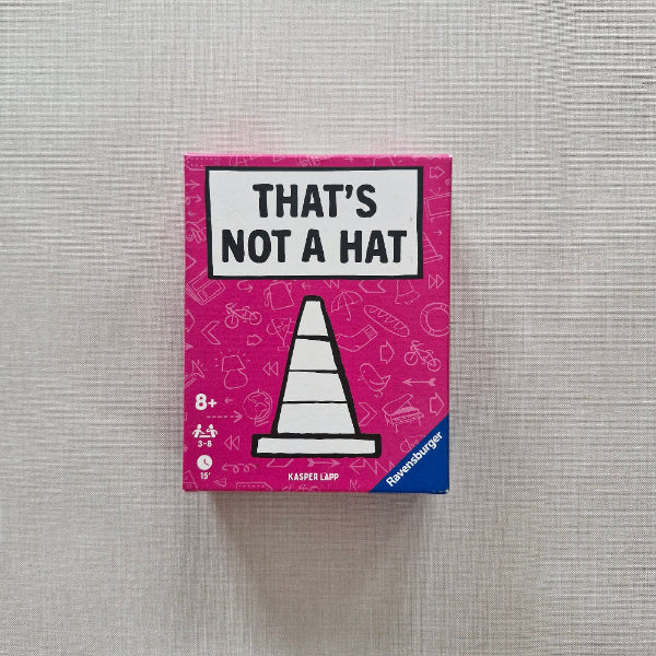 Board game box titled 'That's Not a Hat' on a gray fabric background