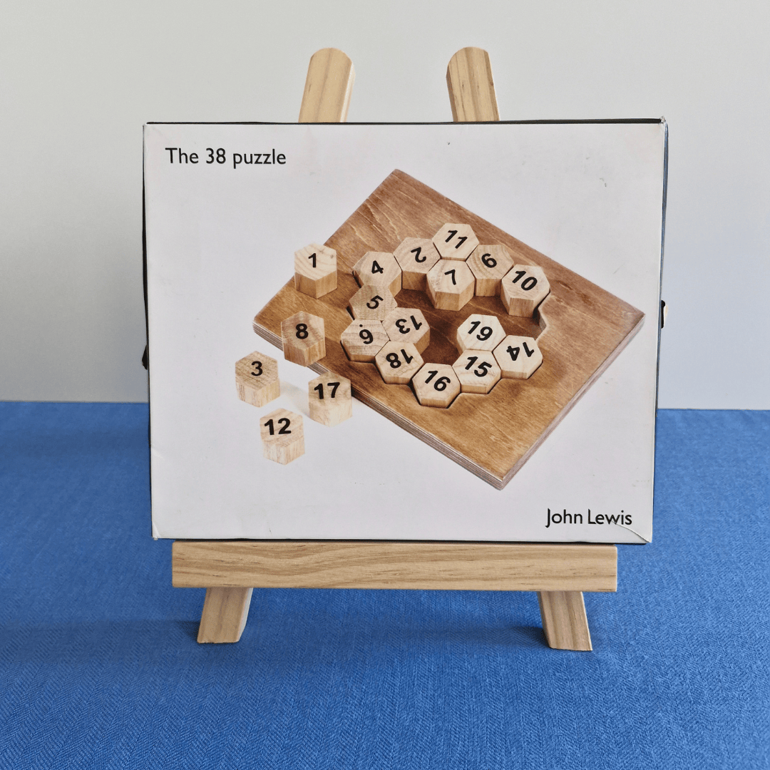Wooden puzzle with numbered hexagonal pieces by John Lewis on a stand against a blue background