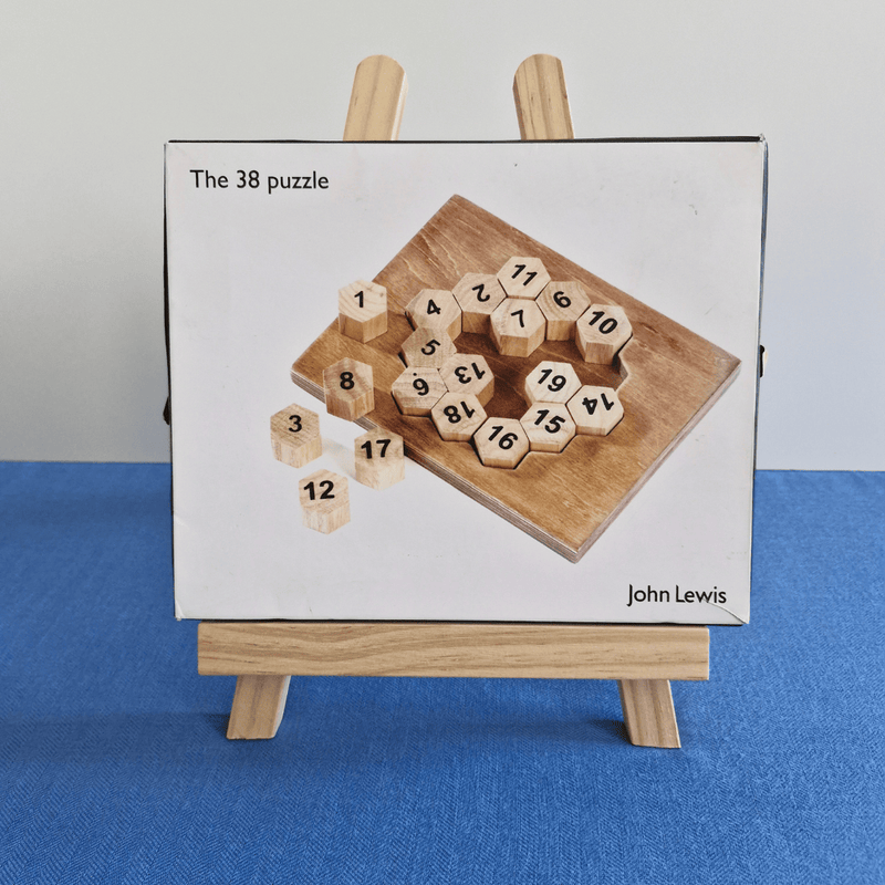 Wooden puzzle with numbered hexagonal pieces by John Lewis on a stand against a blue background