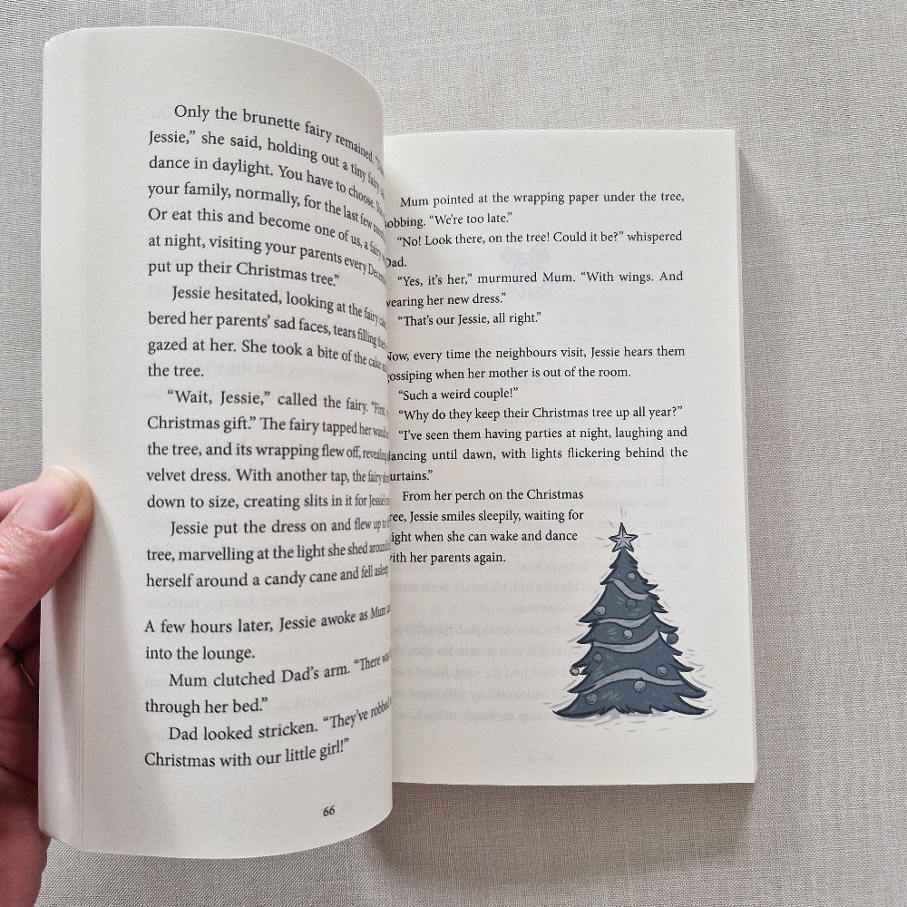 Open book with a Christmas tree illustration on a grey fabric background