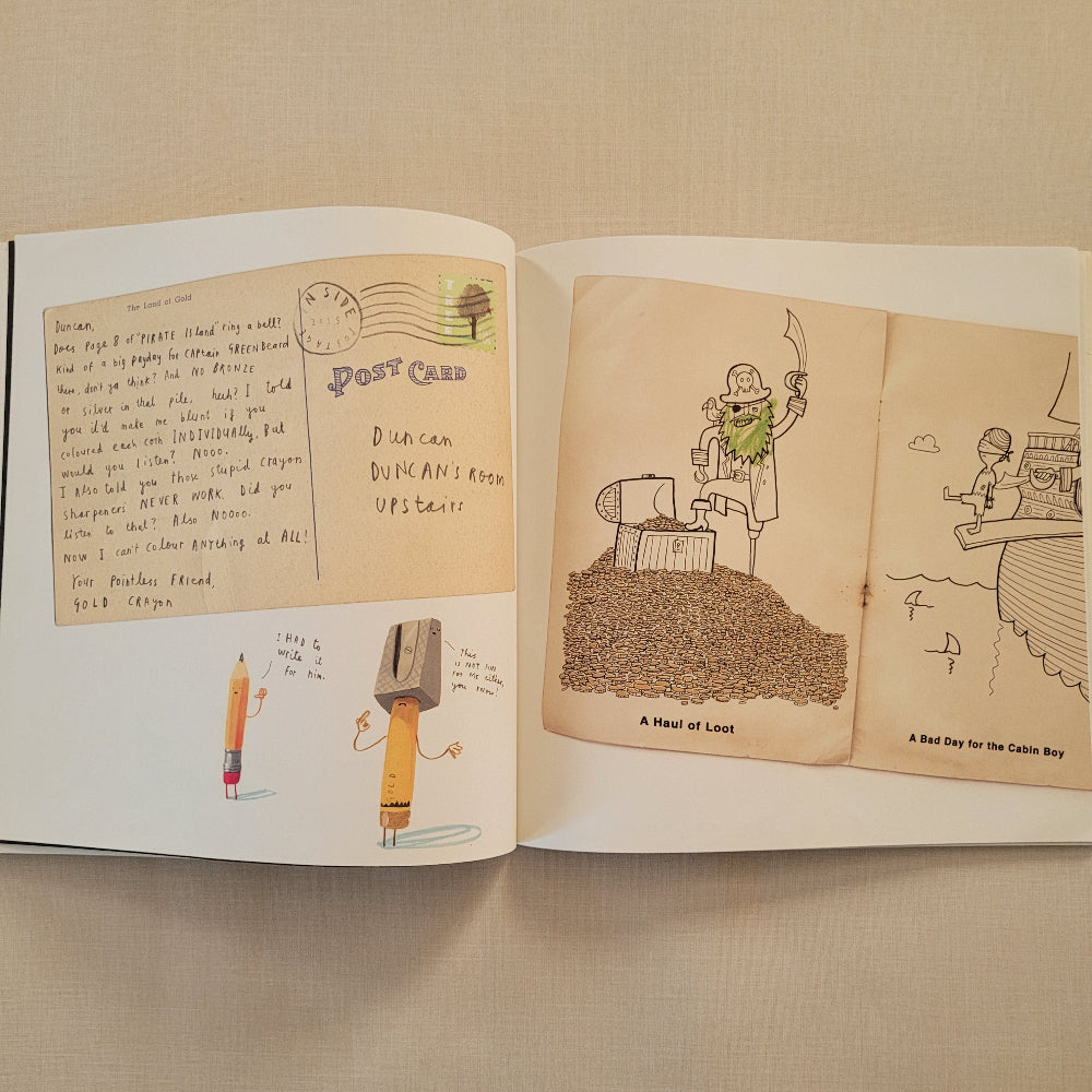An open book or journal spread laid on a beige fabric surface, showing illustrated pages with hand-drawn sketches and handwritten notes.