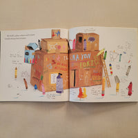 An open children's book spread laid flat on a beige fabric surface, showing colorful illustrated artwork and handwritten notes on both pages.