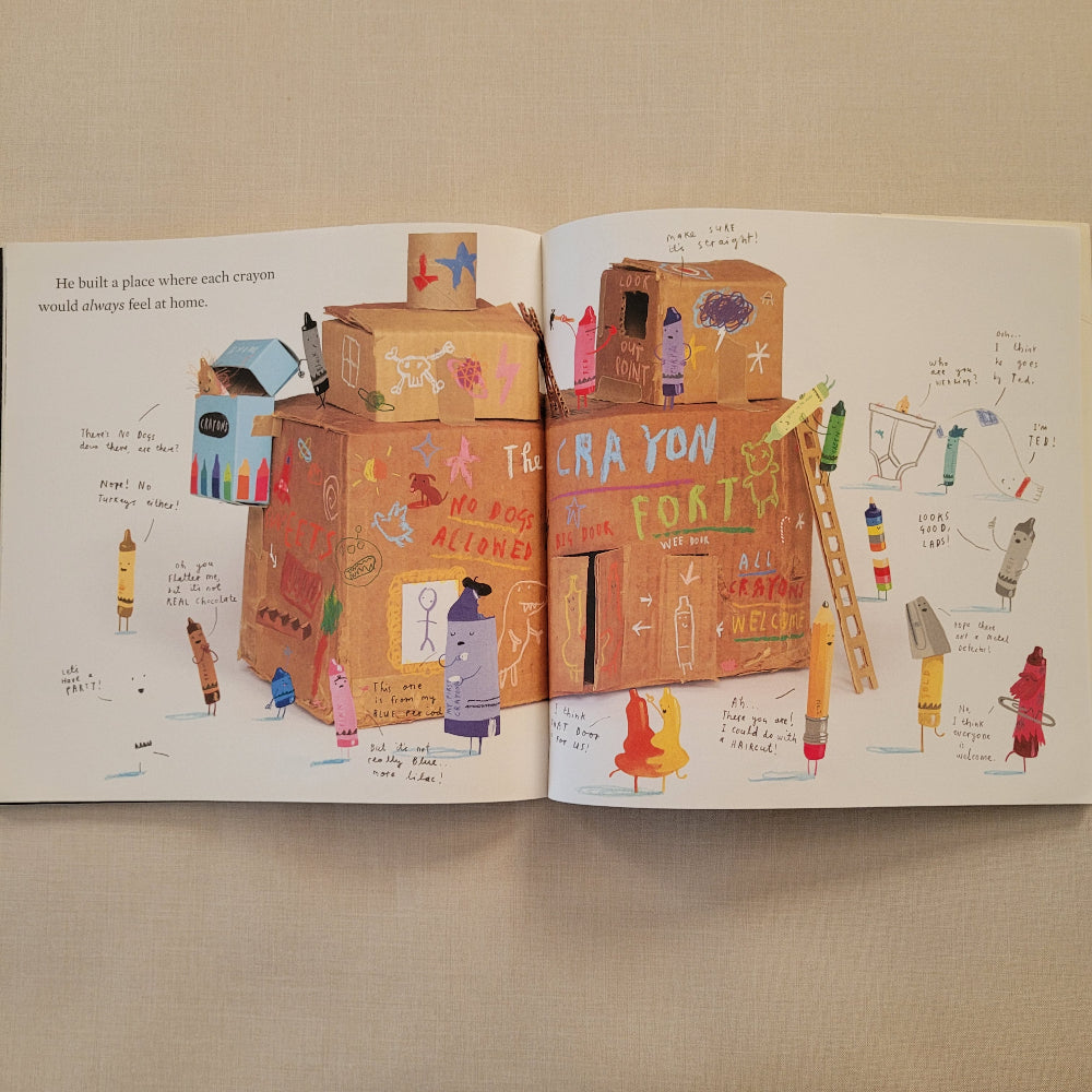 An open children's book spread laid flat on a beige fabric surface, showing colorful illustrated artwork and handwritten notes on both pages.