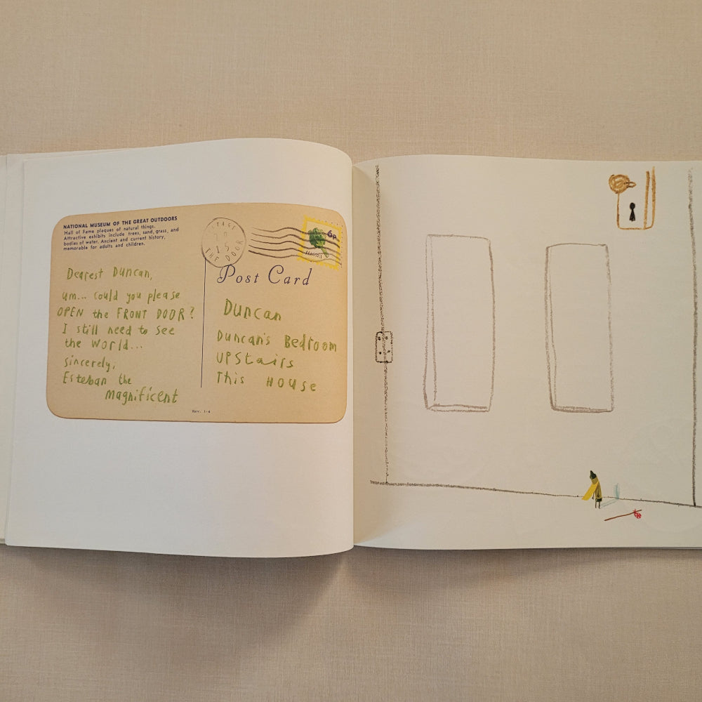 An open book or journal laid flat on a beige fabric surface, showing illustrated pages with a tan postcard-like drawing on the lower page and simple line drawings on the upper page.