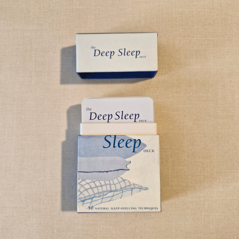 Card deck titled 'The Deep Sleep Deck' on a beige fabric background