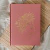 Blush Joy Journal for Mothers with gold floral design on a wooden surface