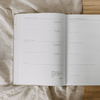 Open planner with daily reflections and notes on a textured fabric surface