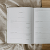 Open journal with a weekly schedule on a textured surface