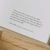 Open book with a motivational quote by Alex Alle on a wooden surface