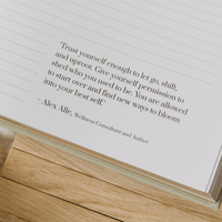 Open book with a motivational quote by Alex Alle on a wooden surface