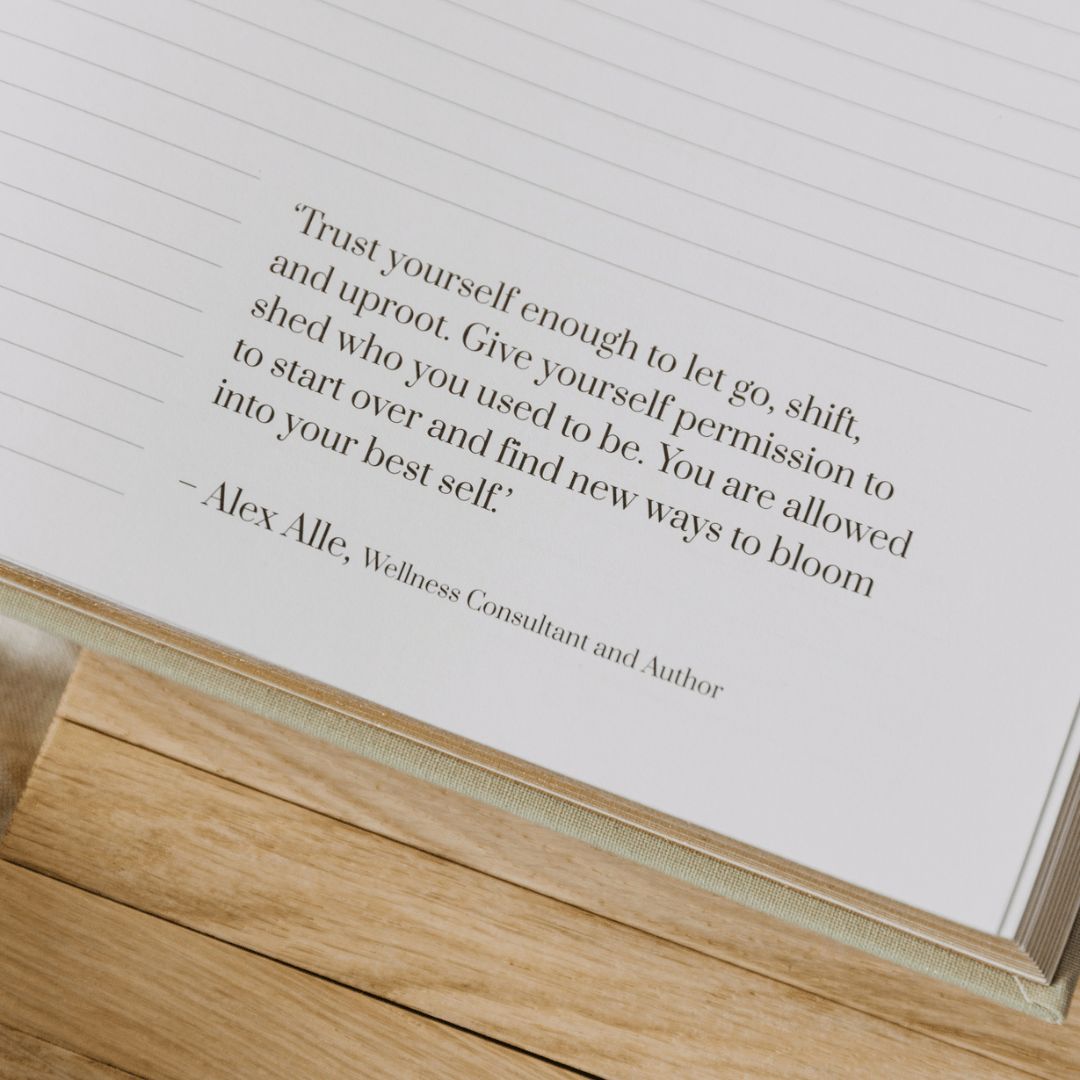 Open book with a motivational quote by Alex Alle on a wooden surface