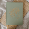 Sage Joy Journal for Mothers with gold embossed design on a wooden surface