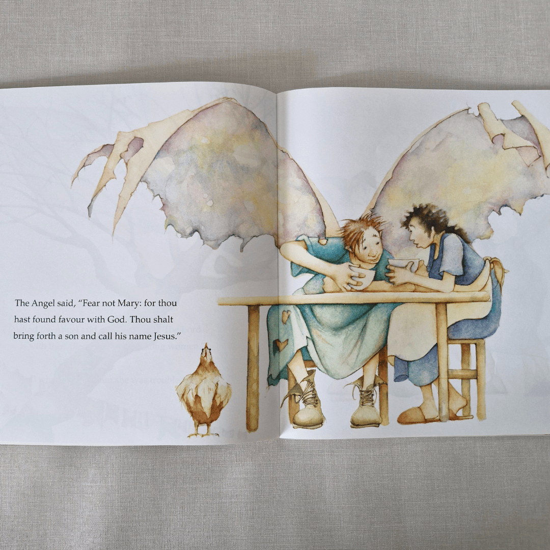 Illustrated book open to two pages with angelic figures and text on a textured fabric background
